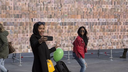 Dos chicas se hacen un selfie frente al mural de tatuajes.