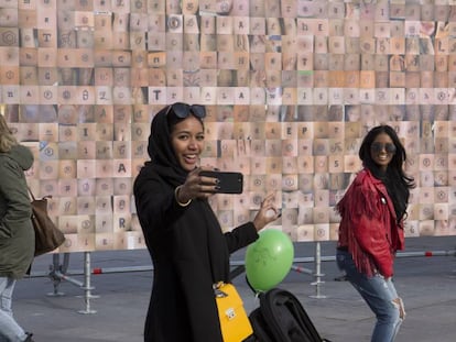 Dos chicas se hacen un selfie frente al mural de tatuajes.