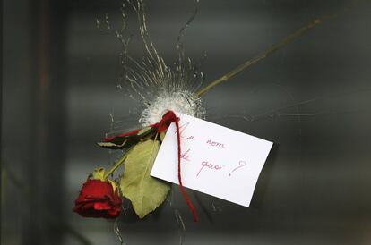 Uma mensagem na qual se lê 'Em nome de quem?' e uma rosa colocada em um buraco de bala em uma janela de um restaurante da Rue de Charrone em Paris, onde ocorreram os ataques terroristas de novembro.