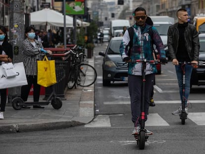 Dos hombres montan en patinete eléctrico en un carril bici emergente en Milán, Italia.