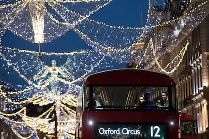 Passengers sit aboard a red London bus as it passes beneath the Christmas festive lights on Regent Street in London on November 25, 2016, one month before Christmas Day. / AFP PHOTO / Justin TALLIS
