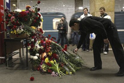 Un hombre deposita flores en recuerdo de las víctimas en una de las estaciones escenario del doble atentado de ayer