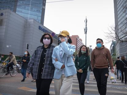 Un grupo de personas pasea con mascarillas por una calle de Pekín