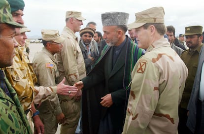 Hamid Karzai (centro), presidente de Afganistán, saluda a un grupo de soldados junto al comandante de las tropas terrestres estadounidenses en Afganistán, el general Franklin Lee Hagenbeck, en la base de Bagram en Afganistán en 2002. 