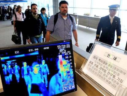 Unos viajeros pasan por un control de temperatura corporal en el aeropuerto de Seúl (Corea del Sur).