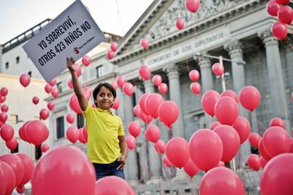 Said, un niño sirio de 8 años, muestra un cartel durante el acto organizado por Save the Children a las puertas del Congreso de los Diputados, en Madrid.