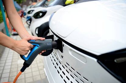 Una persona cargando un vehículo eléctrico.