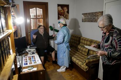 La doctora Pilar Kloppe atiende a Pedro Mesas, de 78 años, que se recupera en casa de neumonía pero ha dado negativo por covid-19. A la derecha, María Ángeles, esposa del paciente.