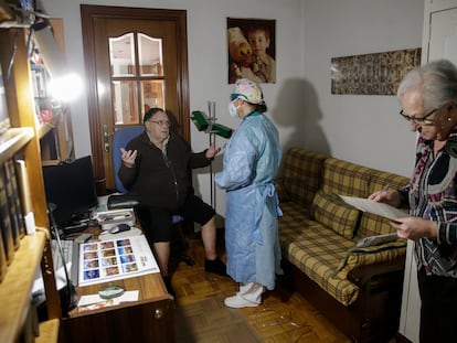 La doctora Pilar Kloppe atiende a Pedro Mesas, de 78 años, que se recupera en casa de neumonía pero ha dado negativo por covid-19. A la derecha, María Ángeles, esposa del paciente.