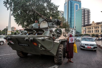 Un monje budista sostiene un cartel junto a un vehículo blindado durante una protesta contra el golpe militar, en Yangon, Myanmar, el 14 de febrero de 2021.