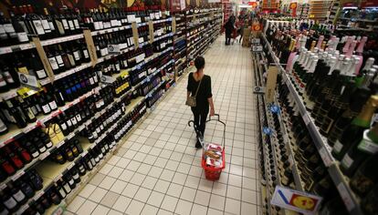 Una mujer con su cesta en la secci&oacute;n de vinos de un hipermercado.