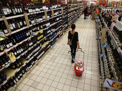 Una mujer con su cesta en la secci&oacute;n de vinos de un hipermercado.