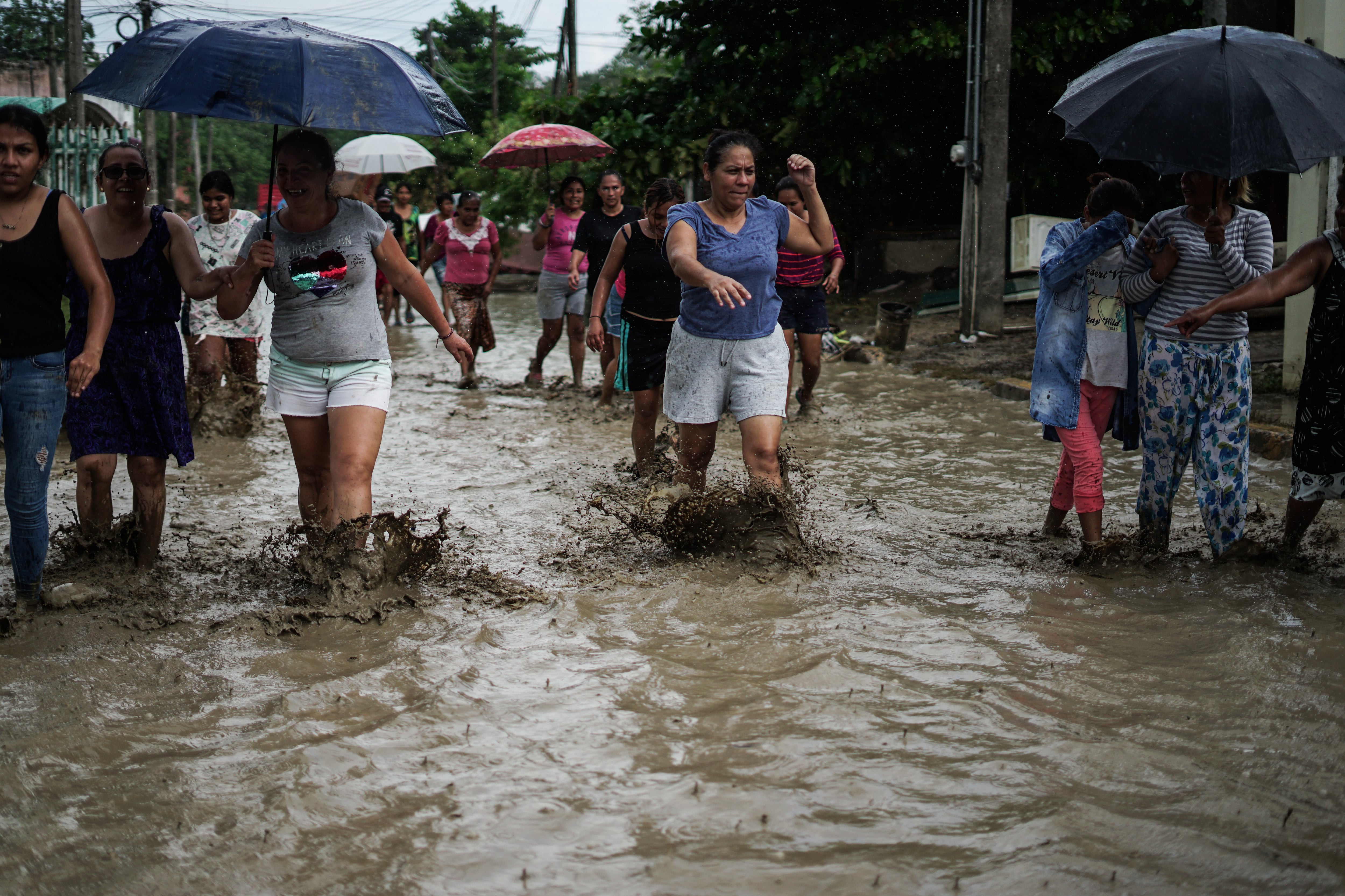 Habitantes de Álamo Temapache caminan entre el lodo que dejó la inundación.