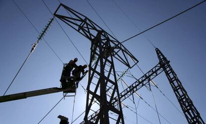 Dos operarios trabajan en una torre del tendido eléctrico. 