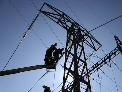 Dos operarios trabajan en una torre del tendido eléctrico. 