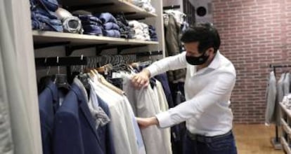 Un hombre protegido con una mascarilla realiza unas compras en una tienda en Madrid.