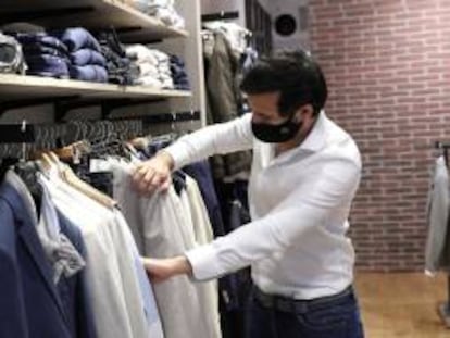 Un hombre protegido con una mascarilla realiza unas compras en una tienda en Madrid.