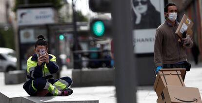 Un repartidor pasa ante una operaria en el centro de Madrid, ayer.