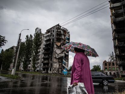Una mujer camina ante unos edificios de apartamentos destruidos por los bombardeos en la ciudad ucrania de Borodianka.