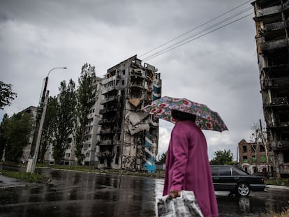 Una mujer camina ante unos edificios de apartamentos destruidos por los bombardeos en la ciudad ucrania de Borodianka.