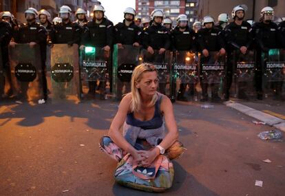 Una mujer que dice ser madre de un manifestante detenido se sienta en el suelo mientras agentes de policía antidisturbios bloquean la calle, durante una protesta contra el presidente serbio Aleksandar Vucic y su gobierno, frente a la principal estación de policía en Belgrado, Serbia, el 17 de marzo de 2019.