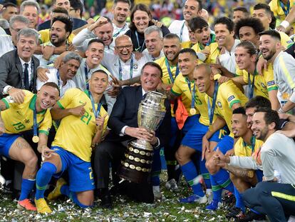 Jair Bolsonaro sostiene la Copa América junto a la selección de Brasil en la edición de 2019.