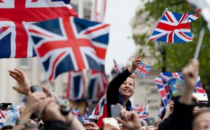 Británicos ondean banderas al paso del carruaje de Isabel II.