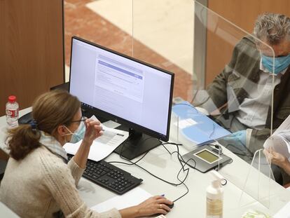 Una funcionaria atiende a dos personas en una oficina de la Agencia Tributaria en Madrid.
