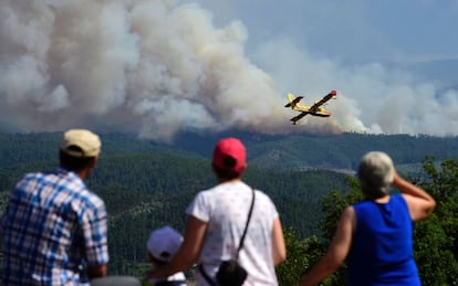 Un grupo de gente observa aun avión Canadair que combate el fuego en Pedrogao Pequeno.