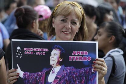 Una mujer sostiene un p&oacute;ster de Juan Gabriel en M&eacute;xico.