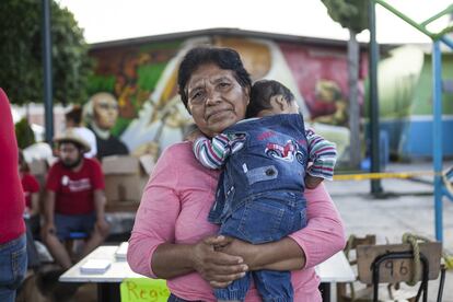 Elvira posa con su nieto en el refugio organizado por los vecinos en la escuela primaria de Tepapayeca, en Puebla. Elvira no sabe cuándo podrá volver a su casa, muchos de los cuartos están agrietados y tiene miedo de que se pueda caer en cualquier momento. “Hace unos días llovió mucho y fui a ver mi casa para ver si seguía en pie. Vi que había muchas goteras en el piso de arriba, entonces me di cuenta de que mi casa estaba llorando como yo”, lamenta.