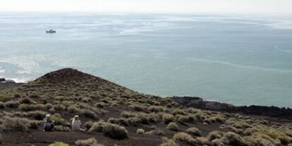 Dos turistas observan el buque del Instituto Español de Oceanografía Ramón Margalef en la zona de la erupción volcánica de La Restinga, al sur de la isla de El Hierro.