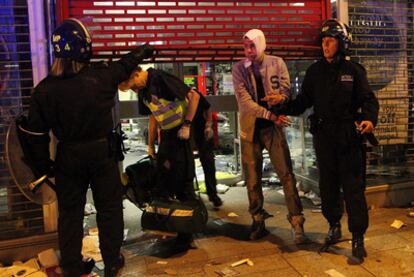 Un hombre herido sale esposado de una tienda después de ser arrestado por la policía por pillaje, en Clapham, al sur de Londres.