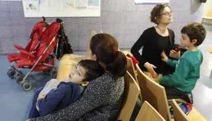 Dos ni&ntilde;os con sus madres aguardan, en la sala de espera del CAP Pare Claret, para ser atendidos