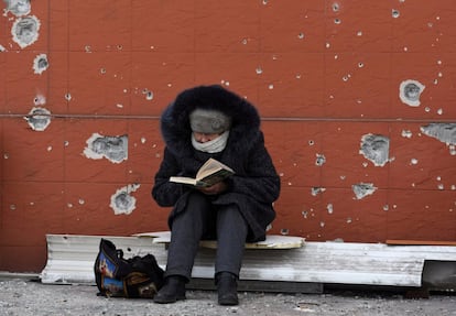 Una mujer lee un libro junto a un edificio alcanzado por proyectiles en Mariupol (sudeste). Las fuerzas rusas se reorganizan y centran su ofensiva en la región de Donbás, en el este de Ucrania, según el último parte de inteligencia del Reino Unido divulgado este lunes.