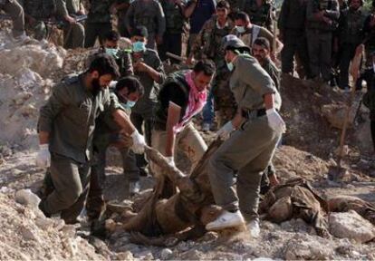La seguridad siria recoge alguno de los diez cadáveres uniformados que fueron encontrados en una fosa común en el pueblo de Jisr al Shughur, al norte de Damasco (Siria).