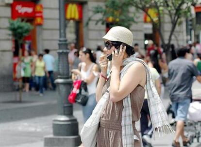 Una turista europea habla con su teléfono móvil mientras pasea por una calle céntrica de Madrid.