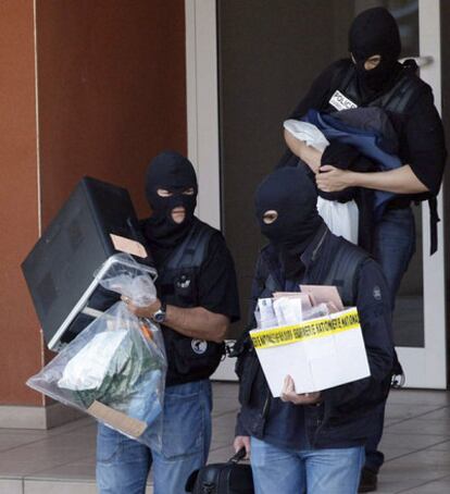 Tres agentes de la policía francesa con algunos de los objetos incautados a los etarras.