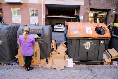 Una mujer tira unos cartones junto a otros restos de basura en la calle Algorta, en el distrito de Carabanchel. 