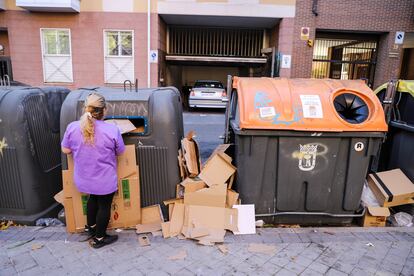 Una mujer tira unos cartones junto a otros restos de basura en la calle Algorta, en el distrito de Carabanchel. 