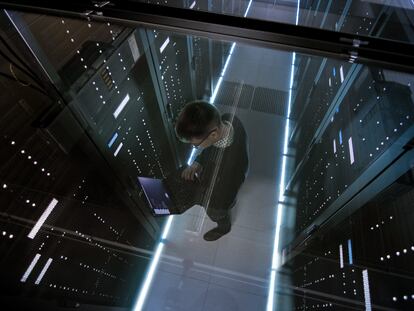 Un hombre revisa en su ordenador el funcionamiento de unos servidores en un centro de datos.