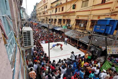 Deportistas luchan durante un partido de lucha libre para aficionados dentro de un ring improvisado en un carretera organizado por los residentes locales, como parte de las celebraciones por el festival hindú Diwali, en Calcuta (India).