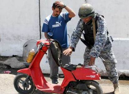 Un policía iraquí inspecciona una moto en un puesto de control en el barrio chií de Ciudad Sáder, en Bagdad.