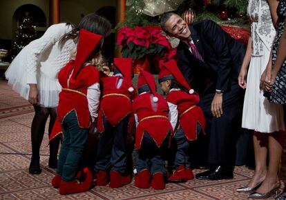El presidente de los Estados Unidos de América, Barack Obama, se divierte con unos niños vestidos como duendes reunidos alrededor de un árbol de Navidad en el National Building Museum de Washington.