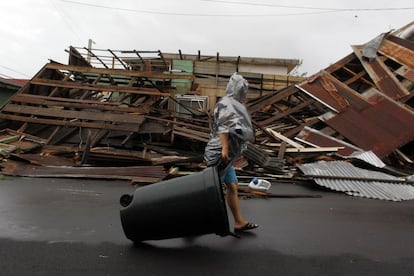 Una mujer empuja un cubo de basura frente a una casa destrozada por la fuerza del huracán María en Fajardo, en el extremo oriental de Puerto Rico.