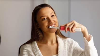 Una chica cepillándose los dientes con un cepillo eléctrico.