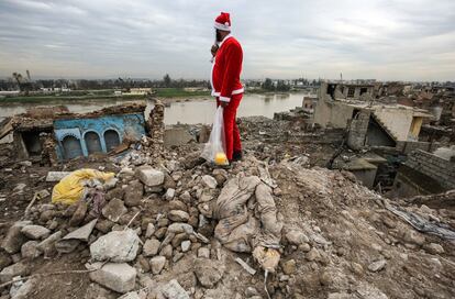 La cristiandad en Irak data desde el primer siglo después de Cristo, cuando se cree que los apóstoles Tomás y Tadeo predicaron el Evangelio en la planicie entre los ríos Tigris y Eúfrates. En la imagen, un joven iraquí vestido con un traje de Papá Noel observa la orilla del río Tigris sobre un montón de escombros en la ciudad destruida de Mosul.