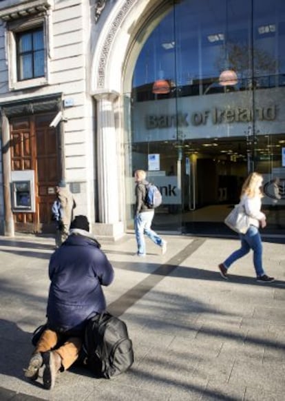 Un hombre pide limosna en Dublín frente a una sucursal del Banco de Irlanda.
