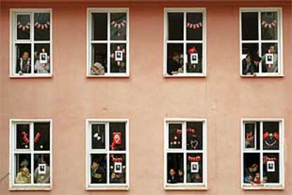 Varias personas se asoman a las ventanas de un colegio electoral para ver cómo abandona el edificio Erdogán, el líder del Partido de la Justicia y el Desarrollo.