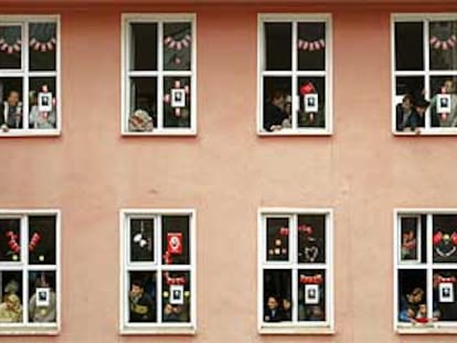 Varias personas se asoman a las ventanas de un colegio electoral para ver cómo abandona el edificio Erdogán, el líder del Partido de la Justicia y el Desarrollo.